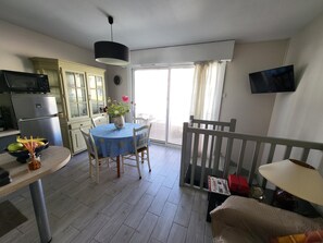 Eine Küche mit Mikrowelle, Kühlschrank und Esstisch mit Stühlen.