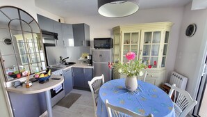 Una cocina compacta con electrodomésticos modernos, un comedor con mesa y sillas, y un amplio ventanal.