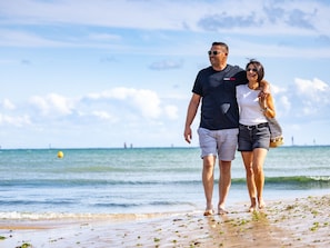 A couple walking on a beach with the ocean in the background. - Apartment 100 m from the sea - 4 guests (Les Sables-d'Olonne)