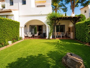 Une terrasse bien entretenue, dotée d’un espace salon extérieur, d’un barbecue et d’une pelouse parfaitement taillée.