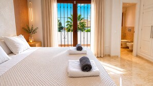 Una habitación de hotel con una cama grande, baño y vistas a palmeras.