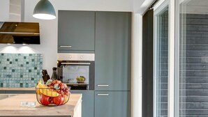 Una cocina moderna con armarios grises, encimera de madera y una cesta de frutas.