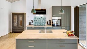 Una cocina moderna con una isla central, luces colgantes y un horno empotrado.