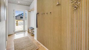 Un interior moderno con un panel de madera, un móvil colgante y vistas a un área exterior a través de un ventanal.