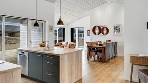 Una cocina amplia con una isla grande, piso de madera y un comedor con mesa y sillas.
