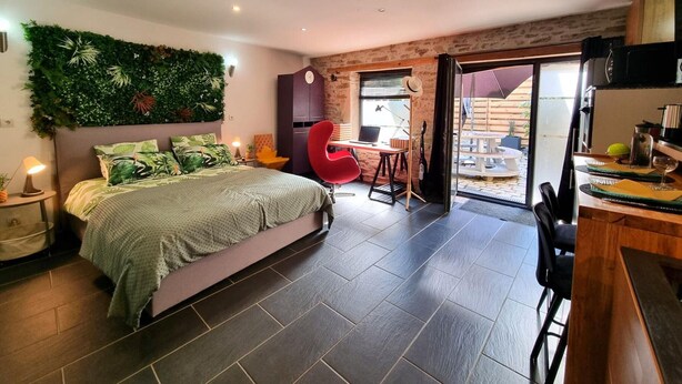 Een slaapkamer met een bed, een rode stoel, een bureau en een groene wand.