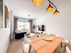A modern living room with a sofa, dining table, and a TV. - Bright apartment, sea view - 4 guests (Estepona)