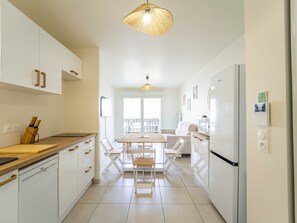 Een moderne keuken met witte kastjes, een houten aanrecht, een eettafel met stoelen en een hanglamp.