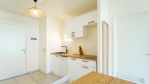 A modern kitchen with white cabinetry, a wooden countertop, a hanging light fixture, and a 'HOME' sign on the wall. - New apartment near ocean - 4 guests (Mimizan)