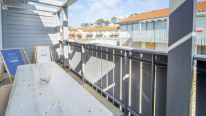 A balcony with a metal railing, a wooden table, and a signboard. - New apartment near ocean - 4 guests (Mimizan)