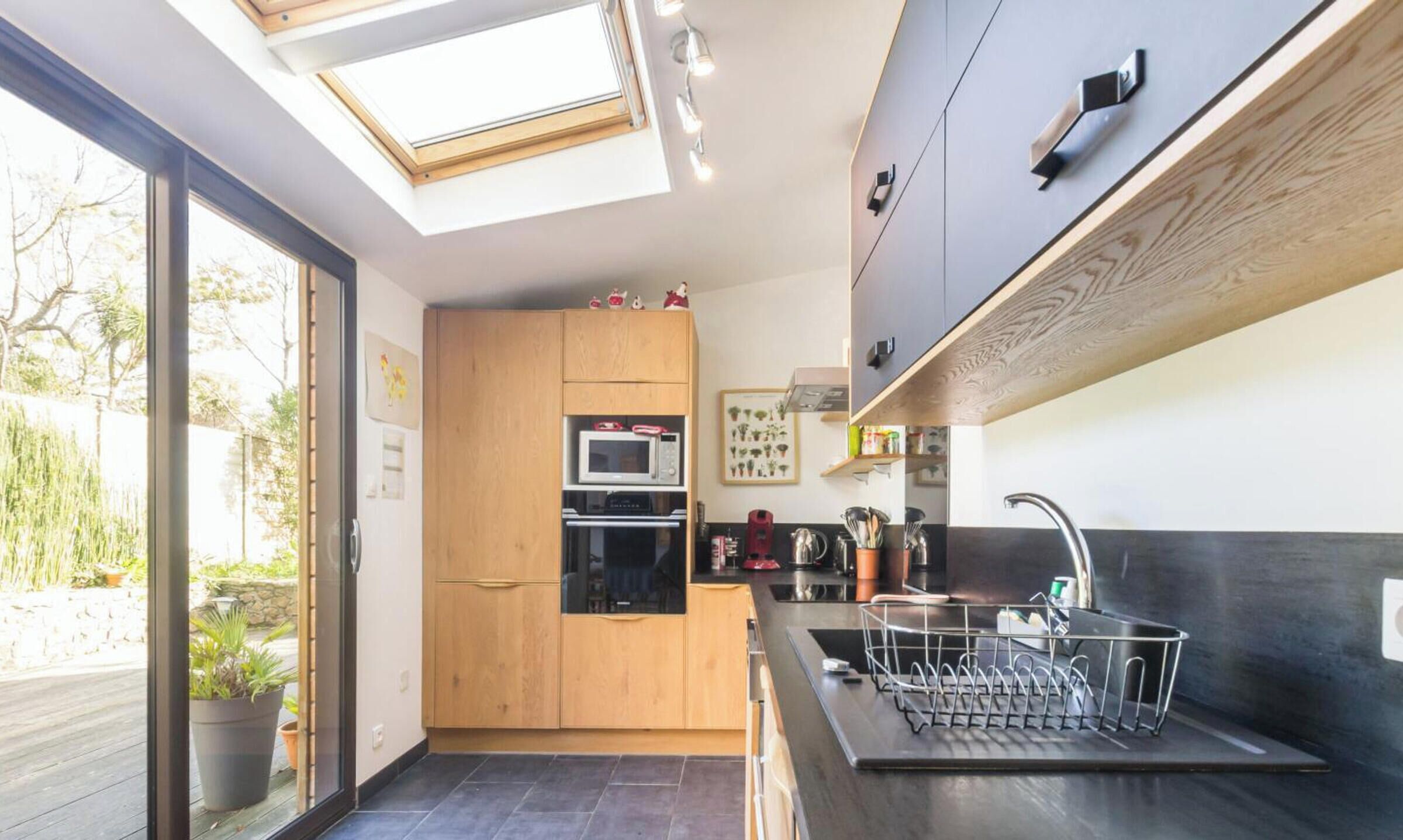 A modern kitchen with skylights, a built-in oven, and a sink with a dish rack.