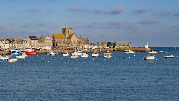 A harbor with boats, a lighthouse, and buildings along the waterfront.