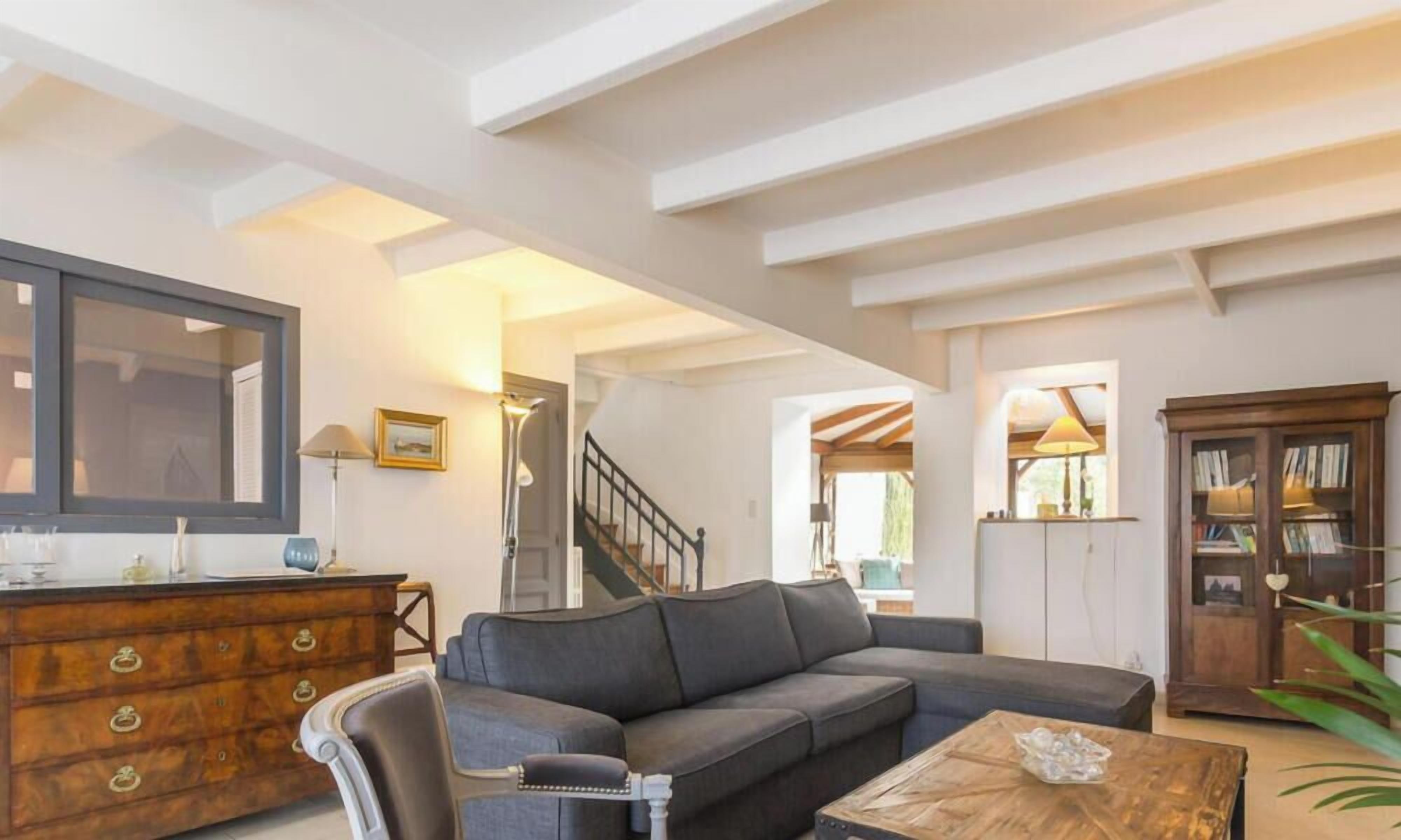 A living room with a sofa, a wooden cabinet, a mirror, and a staircase.