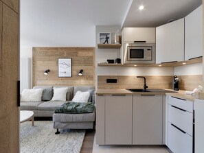 Eine moderne Küche mit integriertem Mikrowellenherd, Spüle und einer Wand in Holzoptik.