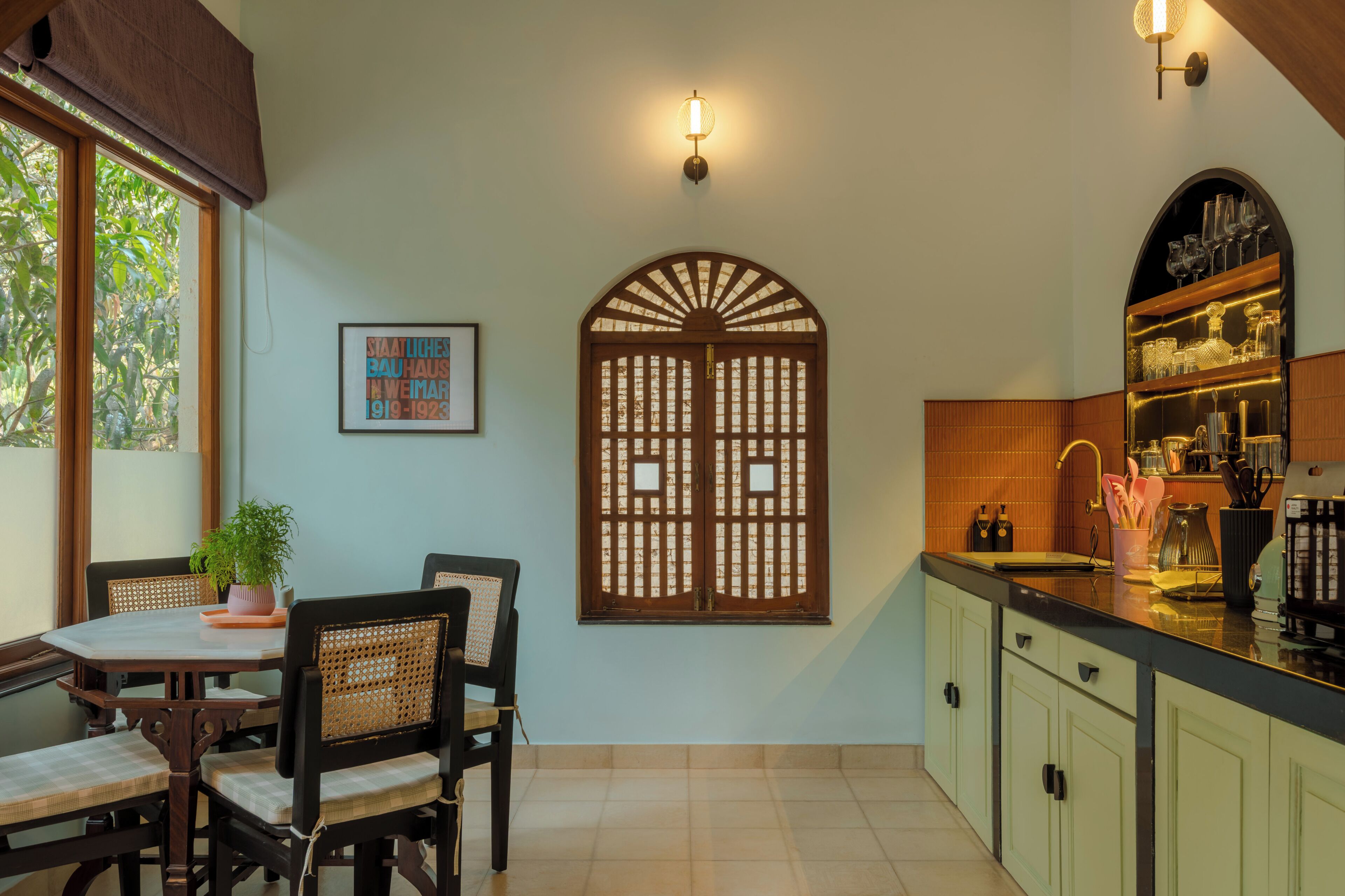 Uma cozinha com área de jantar, uma porta de madeira decorativa e um luminário fixado na parede.