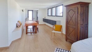 Ein geräumiger Raum mit einem Holztisch, einem gelben Stuhl, einem großen Kleiderschrank und einem Fenster mit vielen Sprossen.