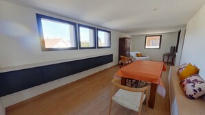 Ein modernes Zimmer mit Esstisch, Stühlen, einer Couch und einem Schrank.