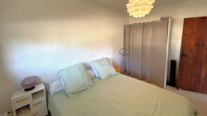 Ett sovrum med en säng, ett nattduksbord, en vägglampa och en dörr.