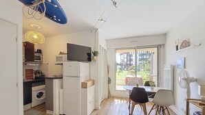 Una cocina compacta con microondas, horno y un televisor encima de un refrigerador blanco.