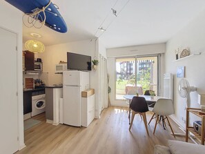 A compact kitchen with a microwave, oven, and a TV on top of a white refrigerator. - Apartment with parking - 4 guests, garden view (Vieux-Boucau-les-Bains)