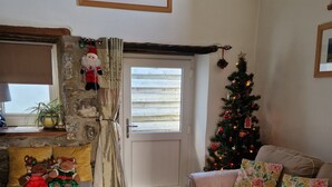 Un salon chaleureux avec un mur en pierre, un sapin de Noël, un canapé et une table basse.