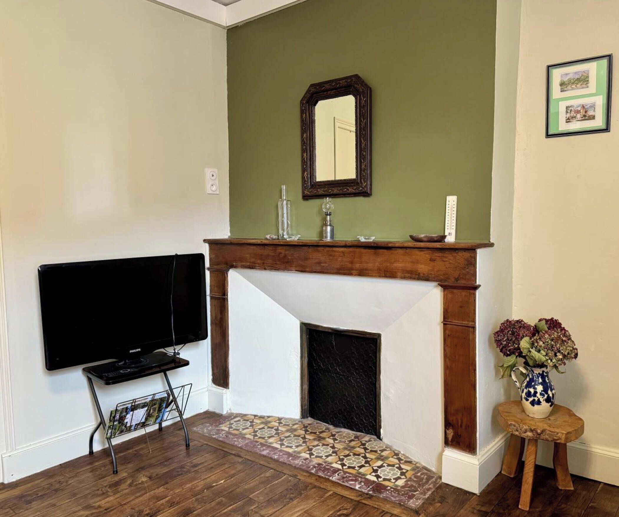 A living room with a fireplace, a television, and a small table with a vase.