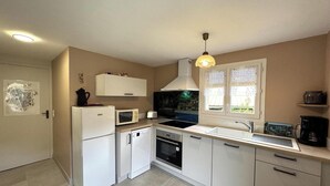 Una cocina compacta con armarios blancos, microondas, tostadora, estufa y lavaplatos.
