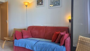 Ein Zimmer mit einer roten Couch, zwei Wandlampen und zwei gerahmten Bildern.