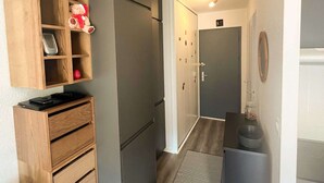 Un pasillo con un armario de madera, una puerta gris y una mesita con un tarro.