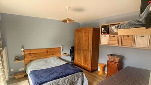 Un dormitorio con cama, armario, estantería con cestas y una silla colgante.