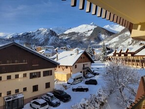 Ein Bergdorf mit schneebedeckten Gebäuden und freiem Blick auf schneebedeckte Berge.