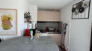 A compact kitchen with a dining table, a coffee machine, and a microwave. - Cozy apartment with balcony - 4 guests (Narbonne)