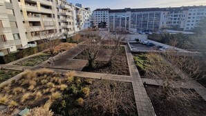 Ett bostadsområde med moderna lägenhetsbyggnader, en parkeringsplats och en välanlagd trädgård med gångvägar.