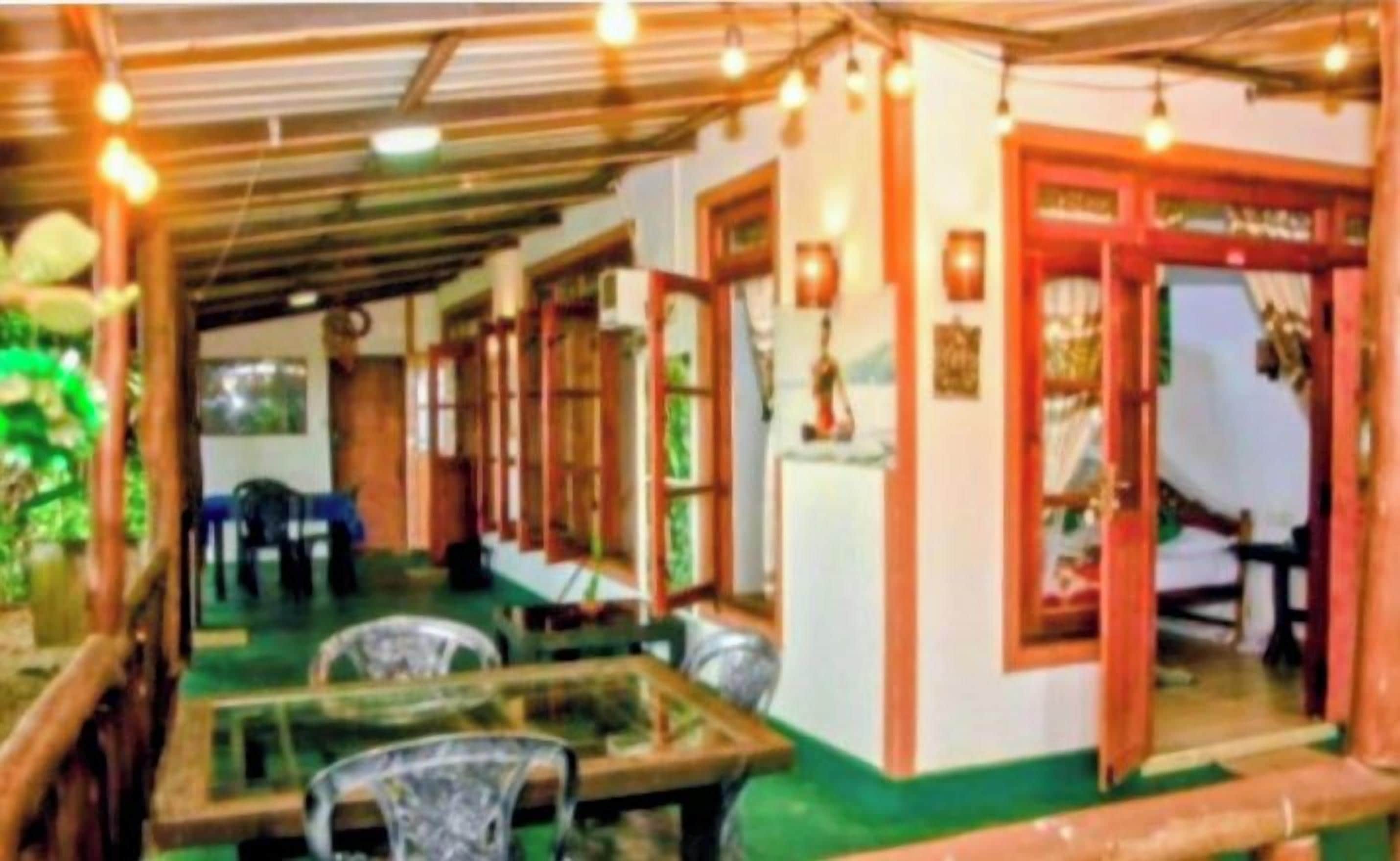 A restaurant with glass tables and chairs, a green floor, and a red door.