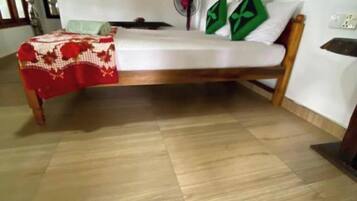 Una habitación con cama, ventilador y una lámpara en la pared.