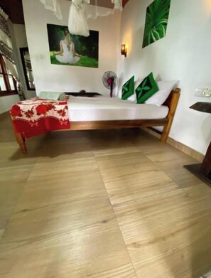 Una habitación con cama, ventilador y una lámpara en la pared.