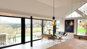 A modern interior with large windows, a dining area, and a view of the outdoors. - Luxury Villa With Garden & Zipline (La Roche-en-Ardenne)