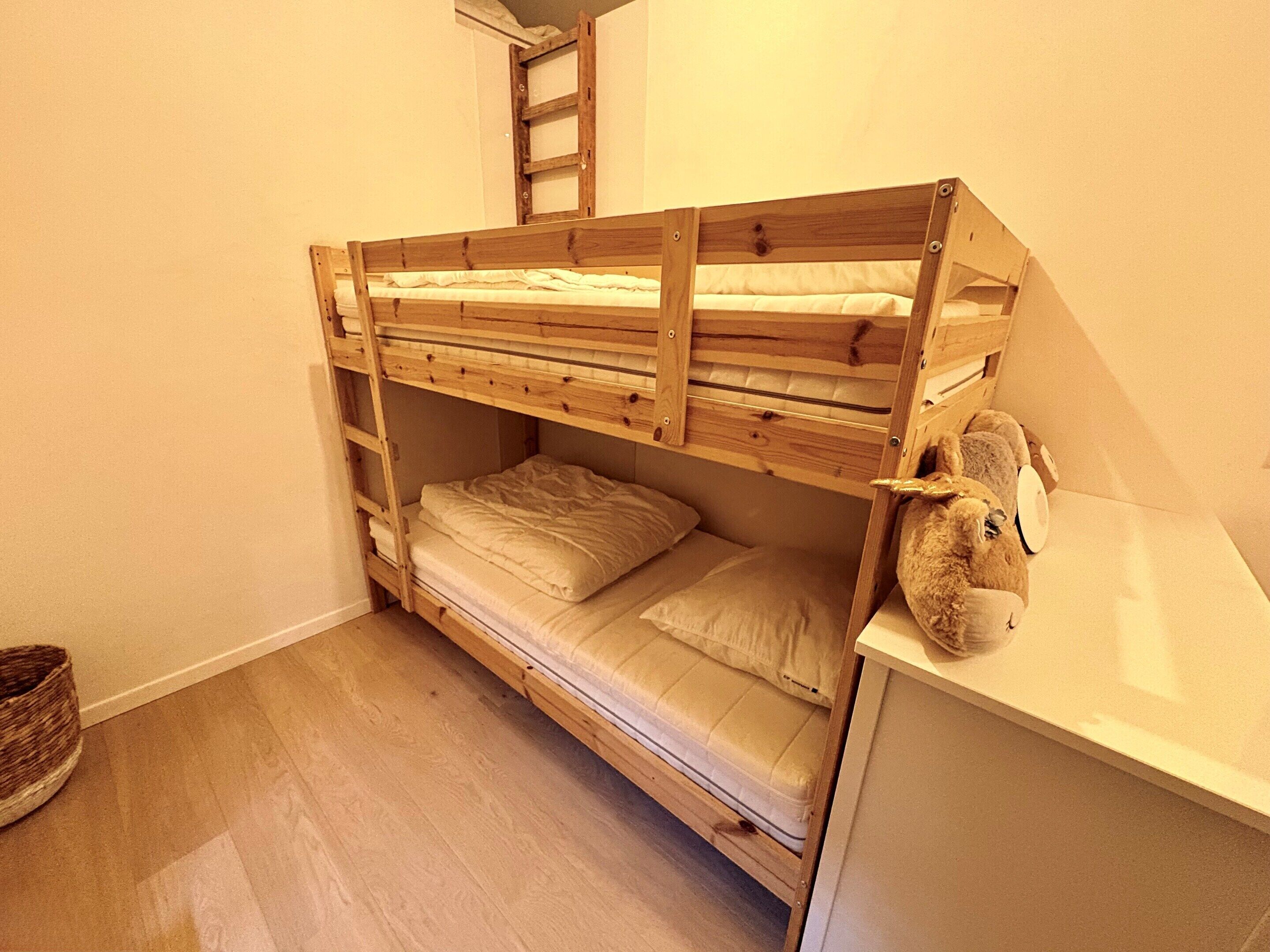 A bunk bed with a ladder, a small desk, and a teddy bear.