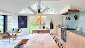 A modern kitchen with a dining area, large windows, and a view of the outdoors. - Luxury Villa With Garden & Zipline (La Roche-en-Ardenne)