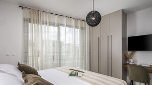 Ein Schlafzimmer mit einem Bett, einem Schreibtisch, einem Sessel, einem Fernseher und einem Kleiderschrank.