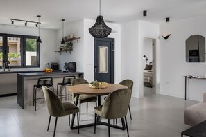 A modern kitchen with a central island, a dining area with a round table and chairs, and a large pendant light. - Villa Medellin Zadarvillas (Novigrad)