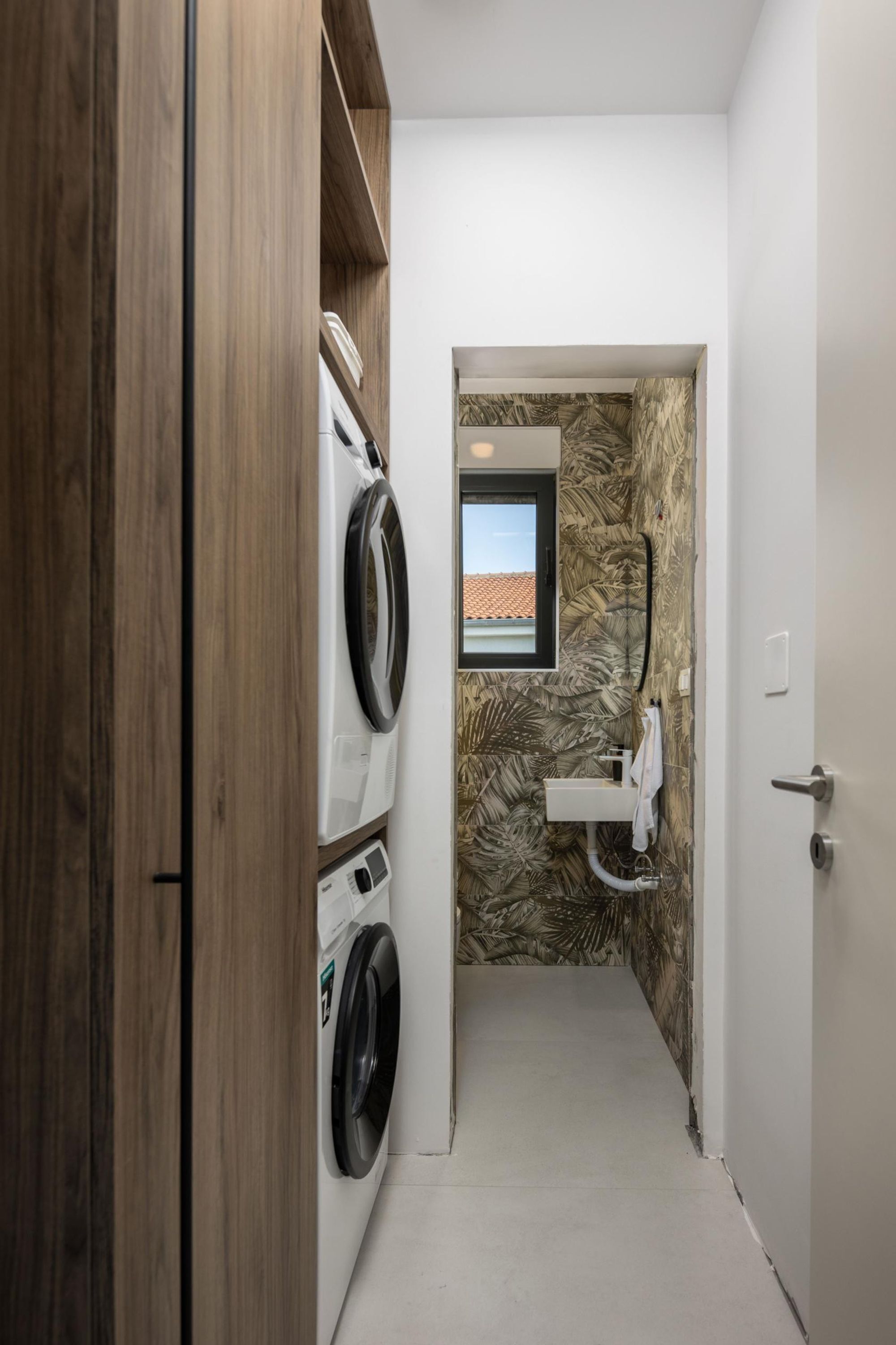 A narrow hallway leading to a bathroom with a sink and a window.