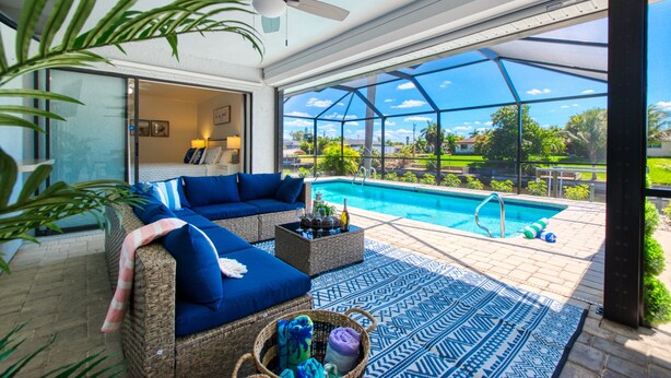 Una stanza luminosa con piscina, mobili in vimini e ventilatore a soffitto.