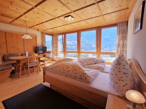 A wooden cabin with a bed, a desk, a chair, and a television. - Cozy Alpine Apartment with Breathtaking Views – Rundblick 3 (Schruns-Tschagguns)