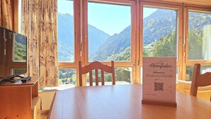 A wooden table with chairs, a TV, and a sign for 'Alpenfeder Gasteiger.'
