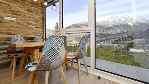 A dining area with a wooden table and chairs, a view of a snowy mountain, and a large window.