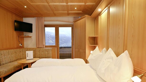 Una camera d'albergo con un letto grande, un divano, una televisione e una finestra con vista.