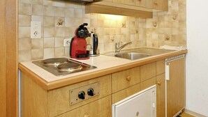 Una cucina con mobili in legno, un lavello doppio, un bollitore e una lavastoviglie.
