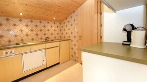 A kitchen with wooden cabinets, a built-in dishwasher, and a coffee machine. - Rundblick 5 – Spacious holiday apartment for 8 guests (Schruns-Tschagguns)