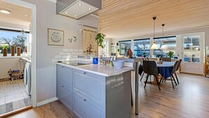 Eine moderne Küche mit einer zentralen Kochinsel, Holzböden und Blick in den Essbereich.